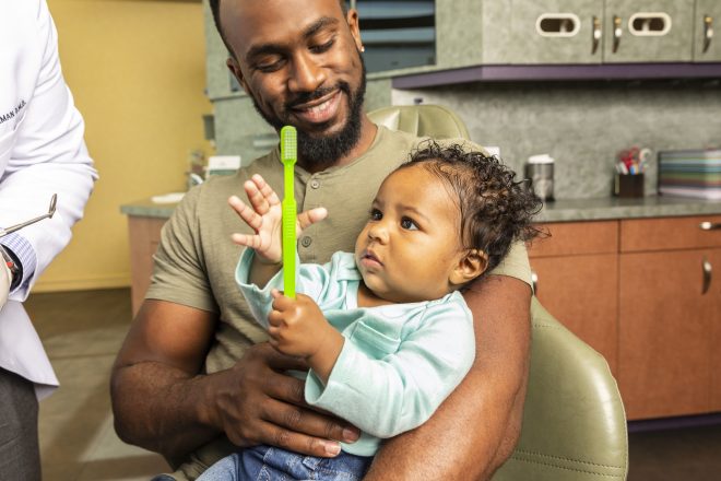 father with baby holding toothbrush